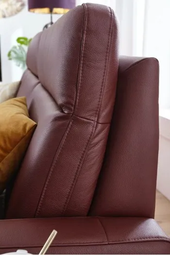 Ecke eines weinroten Ledersofas in Nahansicht.