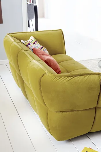Sofa mit gelbem Stoffbezug und großer Steppung von hinten.