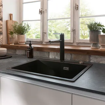 Schwarzes Spülbecken vor den Fenstern eines sanierten Bauernhauses. 
