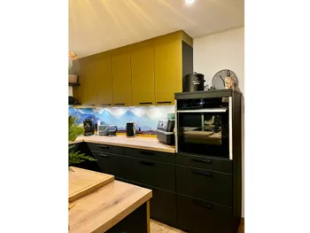Olivgrüne Küche mit schwarzen Unterrschränken und Backofen