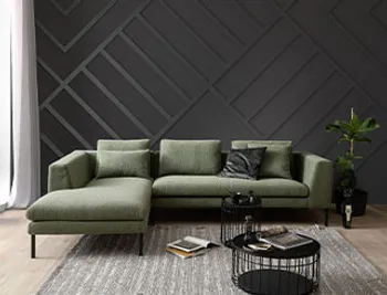 Grünes Boucle Ecksofa mit schwarzen Füßen.