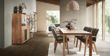 Armlehnstühle in Leder olive mit Massivholzgestell an einem Esstisch aus Massivholz in einem hellen Esszimmer.