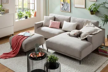 Beiges Ecksofa mit breitem Longchair und schwarzen Füßen.