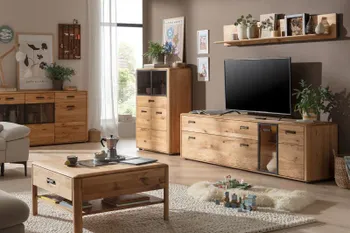 Wohnwand aus hellem Massivholz bestehend aus Wandregal, TV-Board mit Glastür, Sideboard mit Glaseinstätzen und Vitrine mit Glaseinsatz in einem hellen Raum mit dazu passendem Couchtisch.