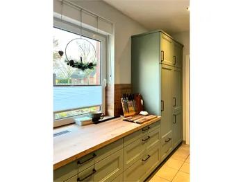 Salbeigrüne Küchenzeile vor einem Fenster