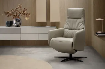 Moderner Designer Sessel mit beigem Leder, vor einer modernen Wohnwand in beige.