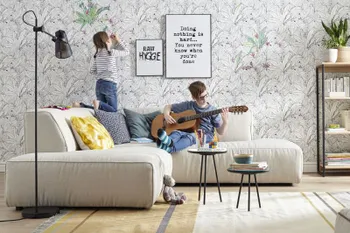 Beiges Ecksofa dekoriert mit mehreren Kissen und bequemer Polsterung, auf der Rückenlehne kniet ein Mädchen und malt die Wand an, ein Junge sitzt auf dem Sofa und spielt Gitarre.