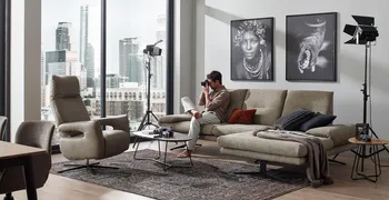 Elegantes Sofa mit eingerollten Armlehnen und schwarzem Gestell und dazu passendem beigen Relaxsessel.