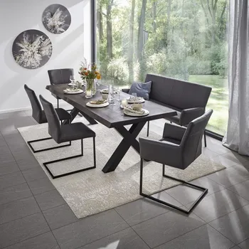 Graue Sitzbank und Freischwinger mit und ohne Armlehne an einem dunklen Holztisch in einem modernen Esszimmer mit großer Fensterfront und beigem Vorhang.
