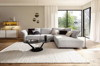 Moderner runder schwarzer Couchtisch mit Keramikoberfläche vor einem grauen Sofa.