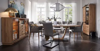 Graue Armlehnstühle und graue Freischwinger mit schwarzem Gestell in einem gemütlichen Esszimmer mit Massivholzmöbeln.