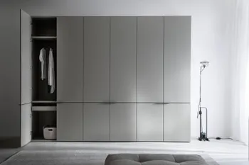 Moderner grauer Kleiderschrank mit sechs Türen, bei dem die erste Türe offen steht und Einblick auf eine Kleiderstange mit Blusen, ein Regalboden und ein Fach freigibt.