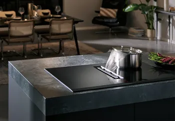Kochfeld von Siemens auf einer Kochinsel. Auf dem Kochfeld steht ein dampfender Kochtop. Der Dampf wird von der integrierten Dunstabzugshaube des Kochfelds perfekt abgezogen. 