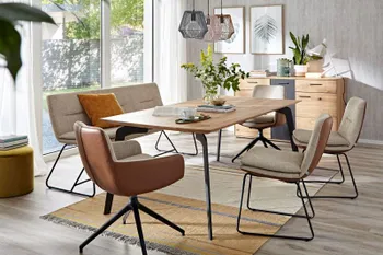 Esstisch mit Massivholzplatte und schwarzen Metallbeinen, um den mehrere Stühle und eine Sitzbank stehen.