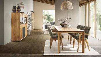 Armlehnstühle in Leder olive mit Massivholzgestell an einem Esstisch aus Massivholz in einem hellen Esszimmer.