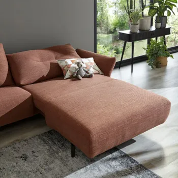 Rotes Sofa mit einem Longchair und dick gepolstertem Rückenkissen mit einer Quernaht.