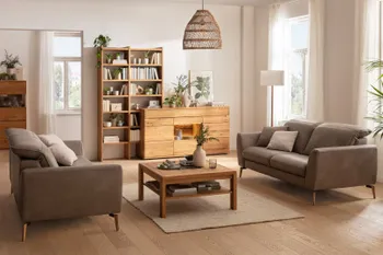 Zwei gegenüber stehende Sofas in braugrauem Leder, dazwischen ein quadratischer Couchtisch aus Holz in einem gemütlich eingerichteten Wohnzimmer.