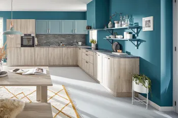 L-Küche mit hellen Holzfronten und türkisenen Hängeschränken in blau gestrichener Küche. 
