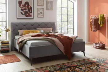 Ein graues Polsterbett in einem Schlafzimmer