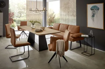 Moderne Stühle und eine Sitzbank mit Lederbezug in Cognac, die um einen Massivholz Esstisch stehen.