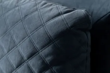 Detailansicht des Kopfteil eines blauen Polsterbetts, das ein Rautenmuster hat.