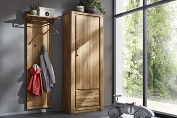 Garderobe in hellem Holz bestehend aus einem Schrank mit Tür und Klapptüre und einer Hutablage mit Kleiderhaken an dem zwei Jacken hängen. 