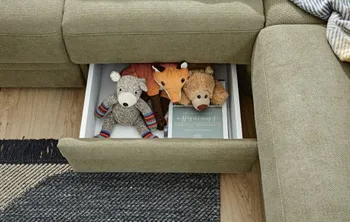 Stauraumschublade unterhalb der Sitzfläche eines grünen Sofas.