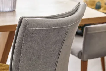 Rückenlehne eines grauen Esszimmerstuhls, der eine Naht in der Mitte der Rückelehne hat.