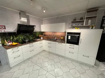 weiße L-Küche, hochgebauter Backofen und Acrylglas Rückwand