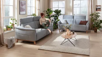 Wohnzimmer mit zwei Zweisitzersofas in hellblauem Stoffbezug und ovalem Couchtisch.