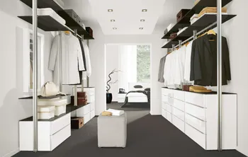 Begehbarerer Kleiderschrank mit vielen Kommoden in unterschiedlichen Größen und Kleiderstangen und Regalböden darüber.