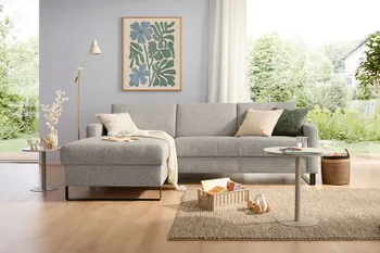 Beiges Ecksofa mit großen Rückenküssen und schwarzem Kufengestell.